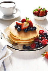 Homemade pancakes with strawberries and blueberries for breakfast. American dessert