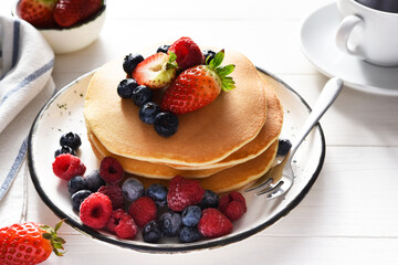 Homemade pancakes with strawberries and blueberries for breakfast. American dessert