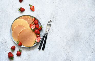Delicate pancakes with strawberries on a concrete background. View from above.