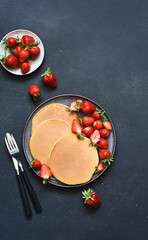 Delicate pancakes with strawberries on a concrete background. View from above.