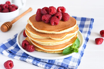 Homemade pancakes with raspberries and jam for breakfast on a white background
