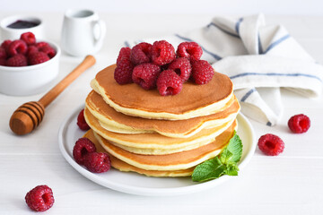 Homemade pancakes with raspberries and jam for breakfast on a white background