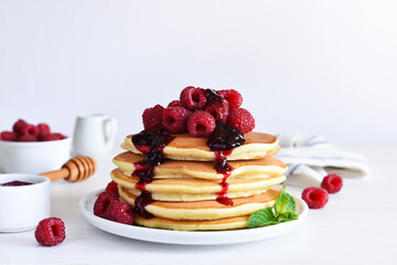 Homemade pancakes with raspberries and jam for breakfast on a white background