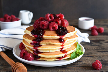 Stack of pancakes.Pancakes with jam and raspberries on a wooden background