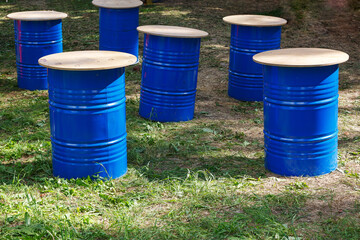 Tables made of blue barrels. Blue barrels are standing on the grass. Outdoor outdoor outdoor cafe. Festival, holiday.