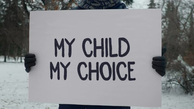 Holding a banner My Child My Choice at the women rights parade. Carrying a banner for women rights movement demonstration. Activist is showing a Banner for women abortion rights march. Pro-choice.
