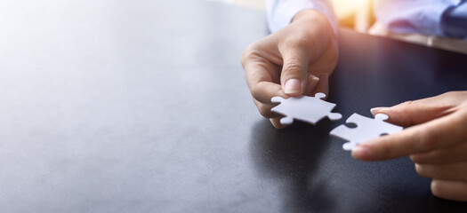 Cropped shot of Businesswoman hand connecting jigsaw puzzle with sunlight effect, Business solutions, success, and Assembling jigsaw pieces, strategy ideas.