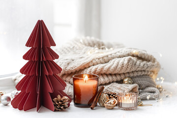 Cozy composition with burning candles, knitted element and decorative details.