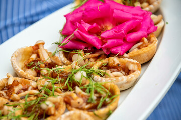 Mushroom tartlets on a plate for serving with a big pink rose as a decoration