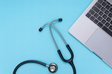 black stethoscope, laptop, blue isolated background