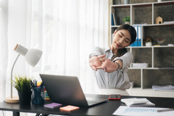 Young business women is relaxing and stretching while working on laptop in office space.