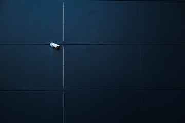 Surveillance camera on the wall of a new modern office building. Concept image for company headquarters security with space for copy.