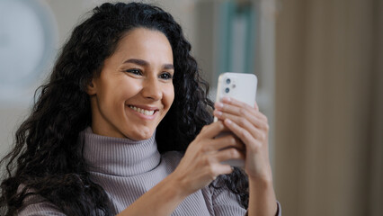 Close up portrait of young happy hispanic woman holding phone browsing social networks smiling female shopper make online order use smartphone communicate remote online chat modern technology concept