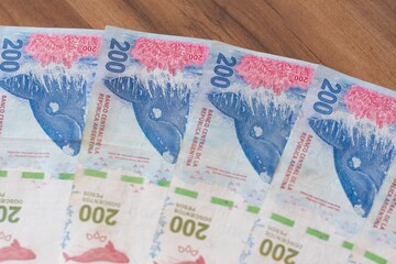 Billetes de 200 pesos argentinos sobre mesa de madera 