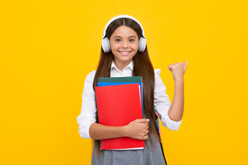 School teen girl in headphones hold book notebooks. Listen to music. Happy excited schoolgirl, positive and smiling emotions.