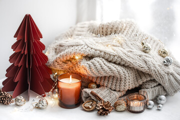 Cozy composition with burning candles, knitted element and decorative details.