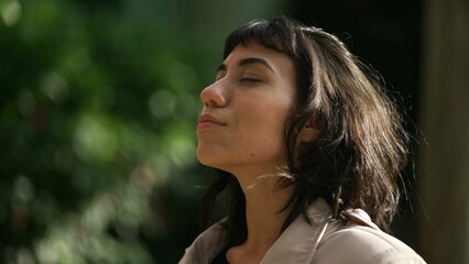 Relaxed young woman with eyes closed standing outside in nature in meditation. Tranquility and relaxation concept. Person in peace and harmony