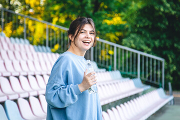 Attractive young female athlete drinks water after a workout.