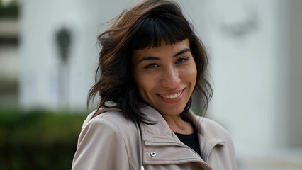 Young woman wearing jacket smiling at camera. A South American latin girl portrait face closeup