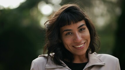 Young woman portrait face closeup smiling at camera. Happy girl standing outside