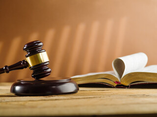 Judgment and justice. On a beige background, an open book and a wooden gavel of the judge. Minimalism. There are no people in the photo. There is free space to insert.