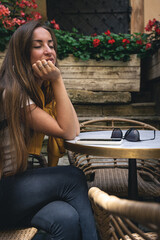 A young woman with smartphone and sunglasses in a cafe on the terrace.