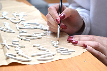 a woman painting some wooden figures with brushes