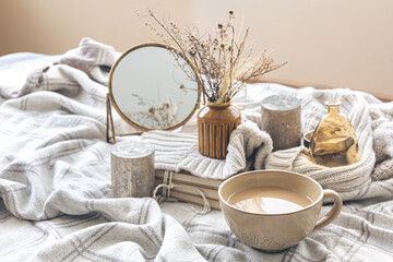 Cozy autumn composition with a cup of coffee and candles in bed.