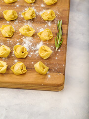 Close-up. Raw dumplings, ravioli on a wooden cutting board sprinkled with flour.. Isolated on a white background. Recipes for home and restaurant cuisine. there are no people in the photo.