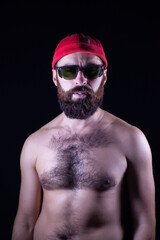 A guy with a naked torso and in a red cap stands on a black background. On his head is a red cap...