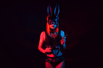 sexy mistress girl in beautiful underwear and a hare mask holds a leather flogger whip for BDSM sex with domination and submission - obrazy, fototapety, plakaty