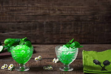 Summer Sicilian dessert granita, frozen juice of fresh cucumber and mint on a wooden background. Summer cooling, tonic cocktail of crushed ice, a kind of sherbet.