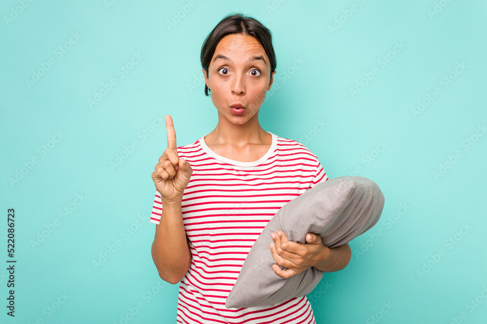 Wall mural Young hispanic woman holding a cushion isolated on white background having some great idea, concept of creativity.