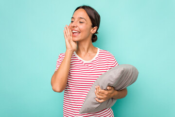 Young hispanic woman holding a cushion isolated on white background shouting and holding palm near opened mouth.