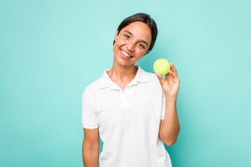 Young hispanic physiotherapy holding a tennis ball isolated on blue background happy, smiling and cheerful.