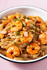 Pad thai with shrimp and peanuts on a pink background.