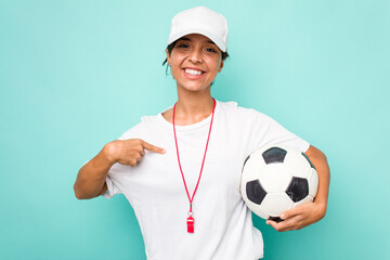 Young hispanic soccer referee woman isolated on blue background person pointing by hand to a shirt...