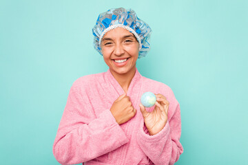 Young hispanic woman holding bathtub ball isolated on blue background laughing and having fun.