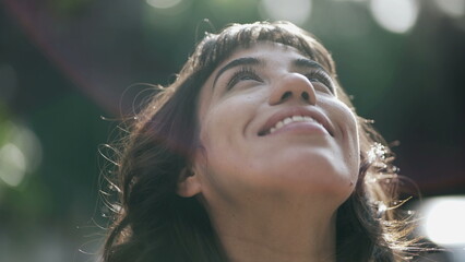 Contemplative young woman looking up at sky with HOPE and FAITH. Spiritual South American girl...