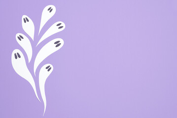 Halloween design, group of cute white ghosts flying on lilac background, pastel color trendy composition with copy space.