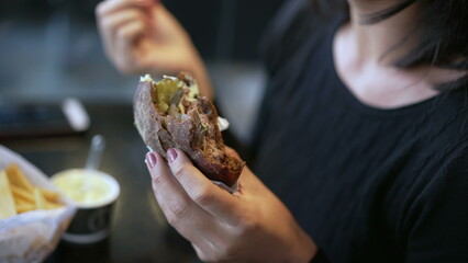 Closeup hand holding cheeseburger. Female hands half eaten burger