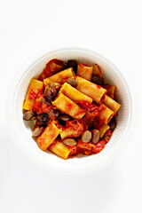 Italian tortiglioni pasta puttanesca with tomato sauce and black olives on the white table in a box for delivery