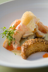 Prawn in creamy sauce, with red caviar, herbs and citrus dairy foam, and seed bread.