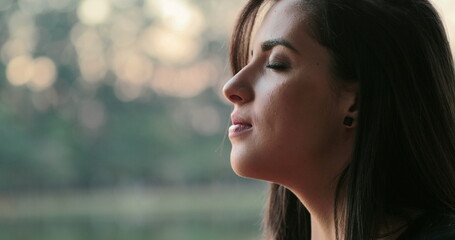 Young woman with eyes closed taking a deep breath outside at the park