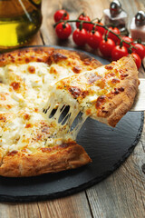 A slice of hot Italian pizza with stretching cheese. Pizza four cheeses with basil.