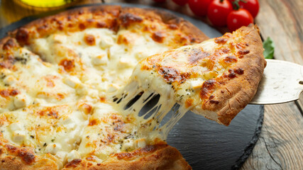 A slice of hot Italian pizza with stretching cheese. Pizza four cheeses with basil.