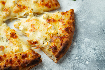 Italian pizza four cheeses with stretching cheese and basil on a light concrete background.