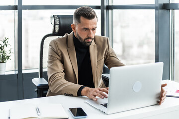 Attractive businessman working on a laptop in the office