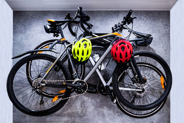 Two bicycles hang on a hanging structure on the wall in the apartment. Bicycle storage solution at home. Sports and safety. Sports equipment, eco-friendly transport, save nature