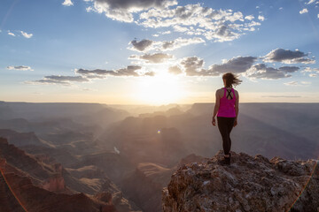 Adventurous Traveler standing on Desert Rocky Mountain American Landscape. Cloudy Sunny Sunset Sky. Grand Canyon National Park, Arizona, United States. Adventure Travel